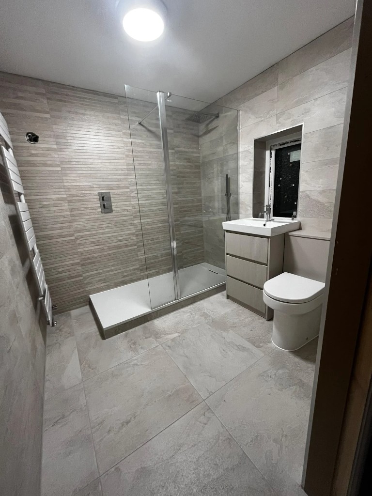 Finished shower room with stone-effect wall and floor tiling